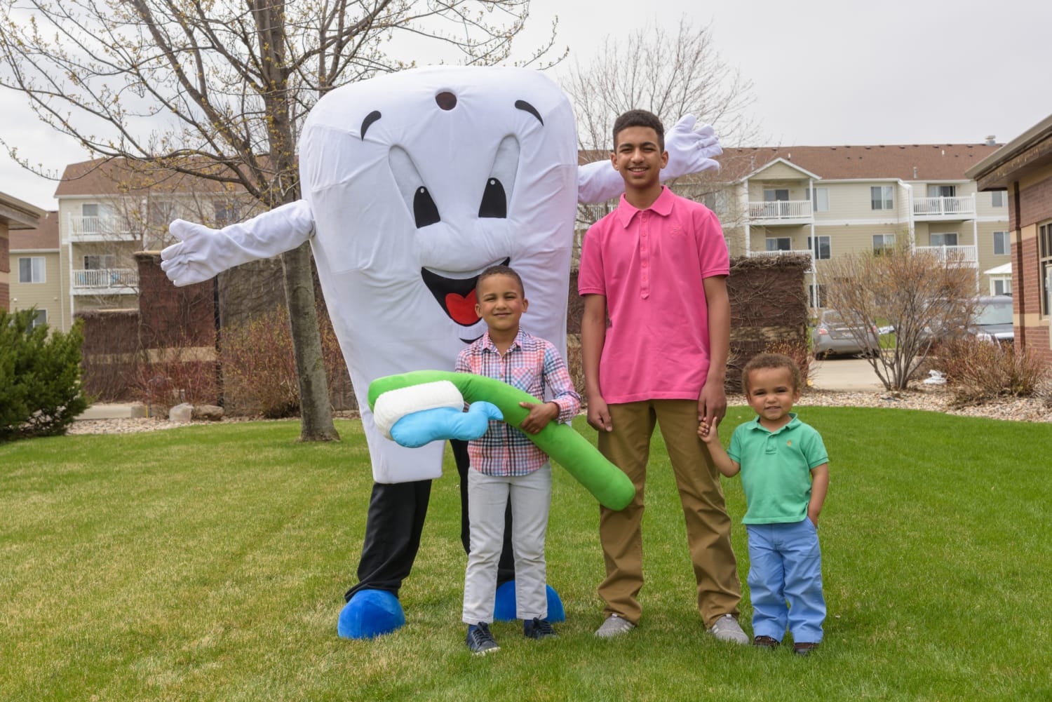 3 kids standing with person dressed up as tooth