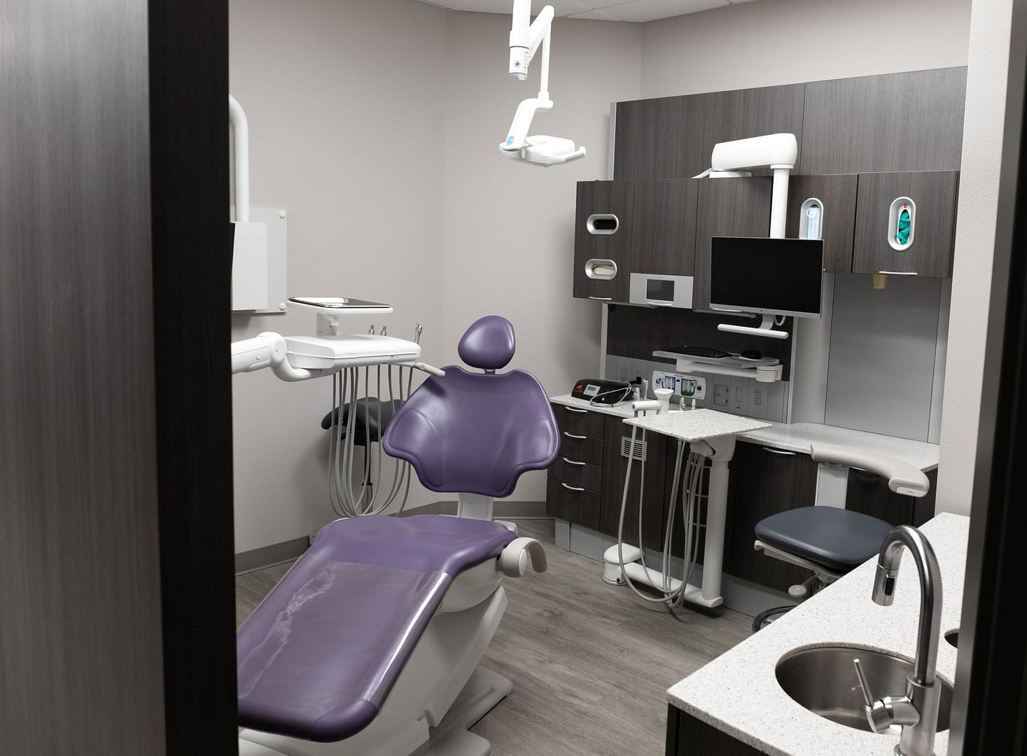 exam room with purple dental chair and gray cabinets