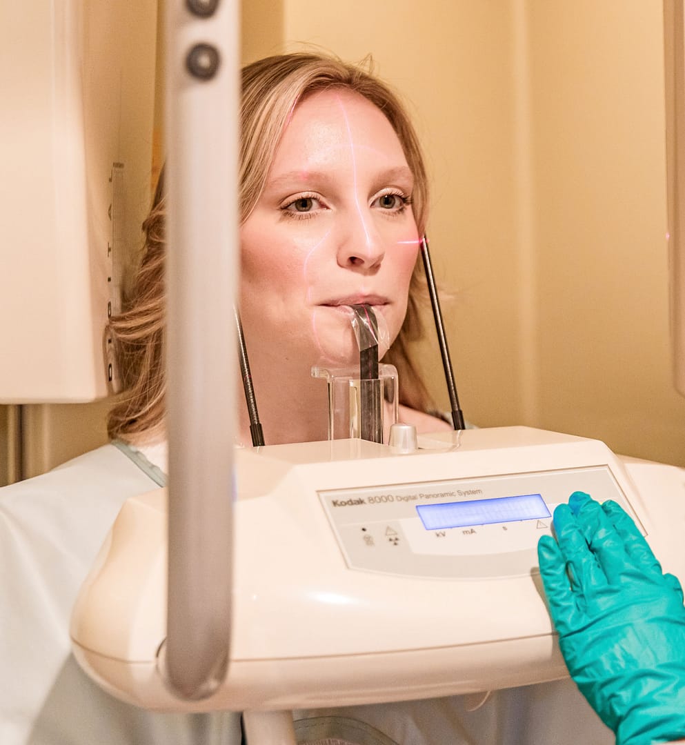 team member taking dental x-rays of adult female patient