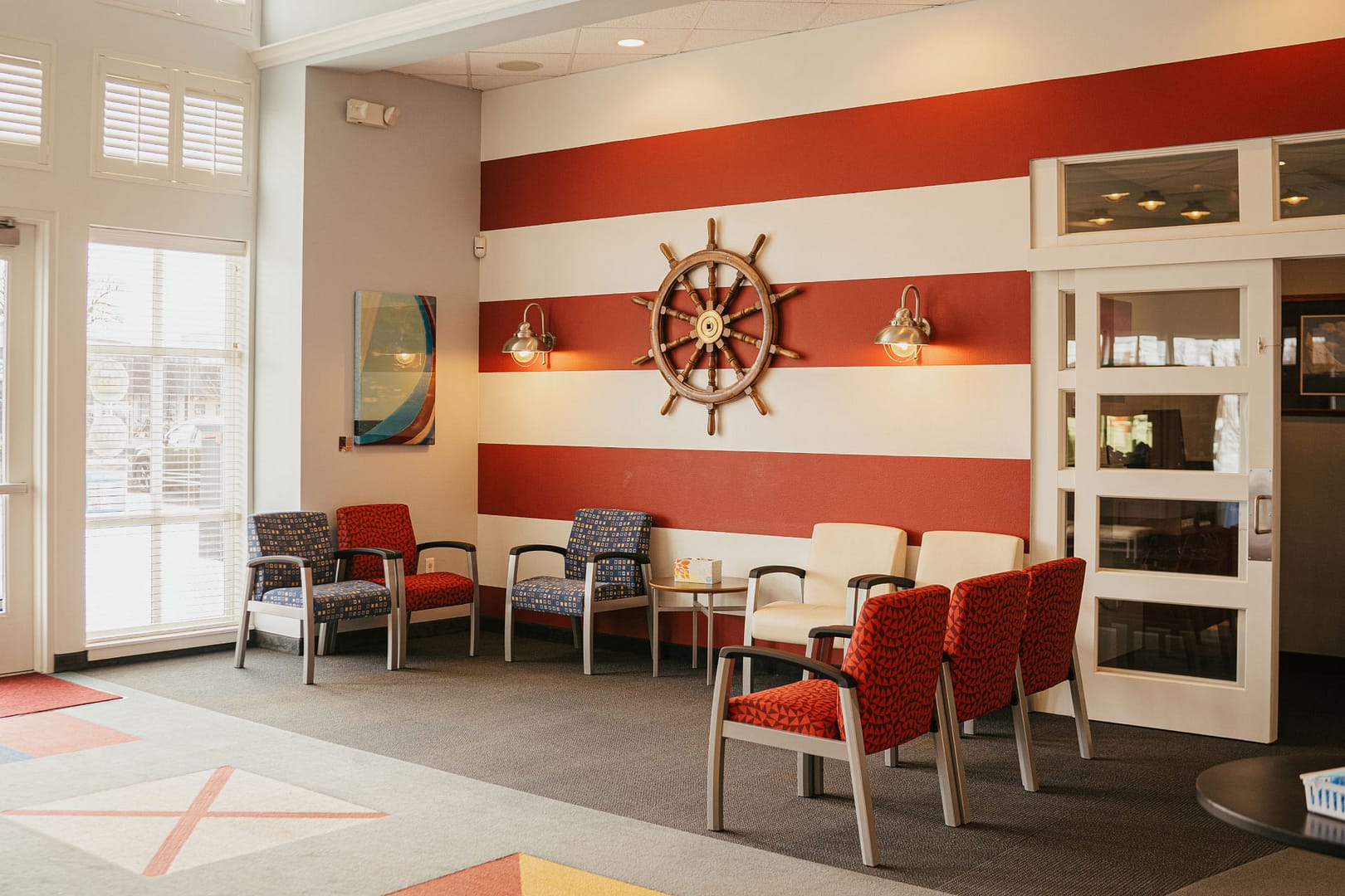 reception area with red striped wall and sailing boat wheel on wall