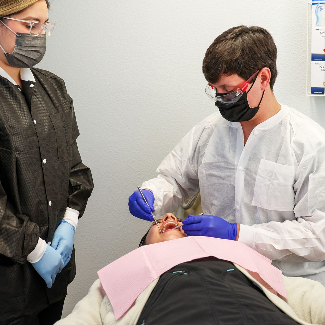 dentist and assistant performing dental procedure on patient in exam room