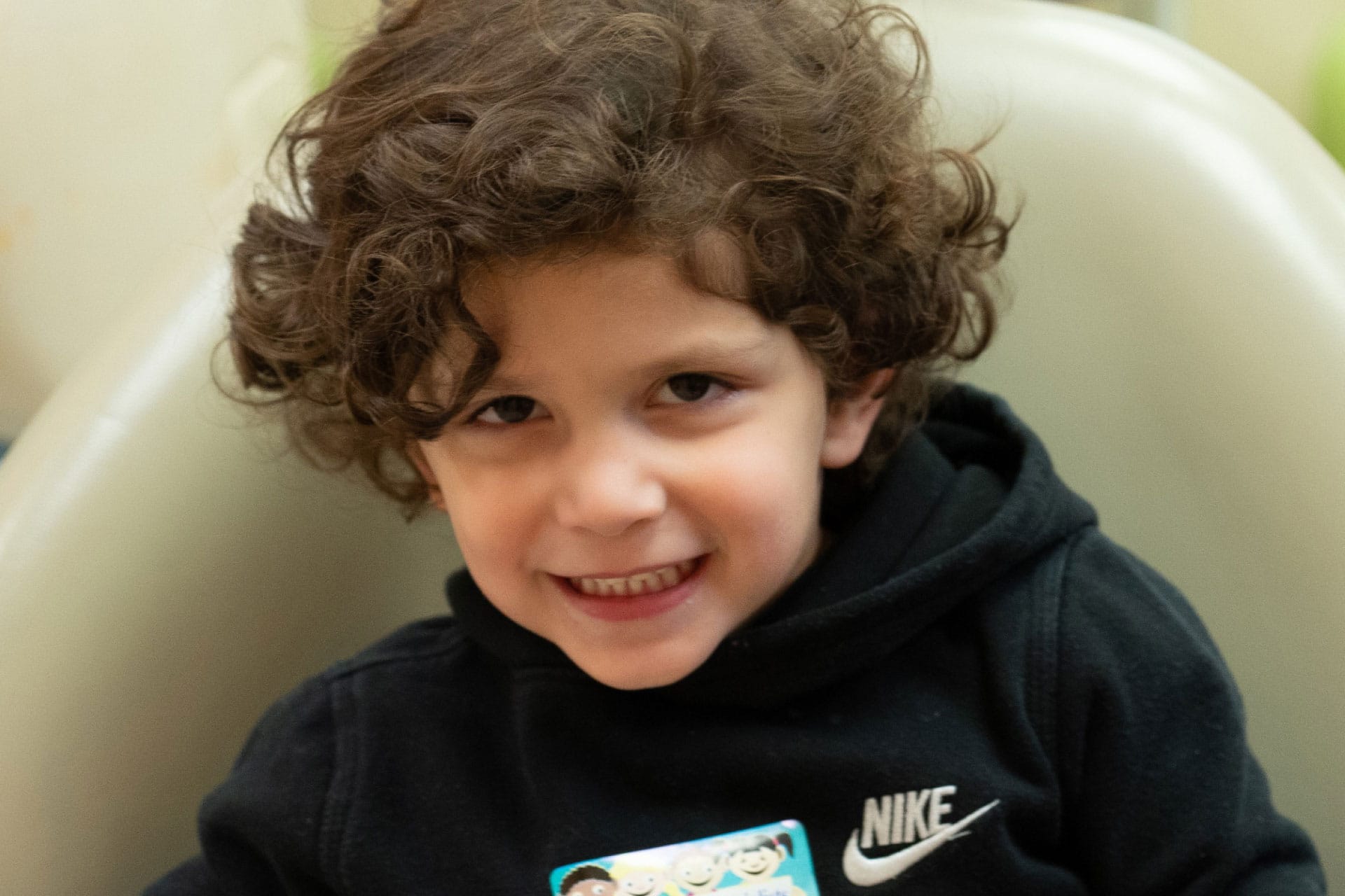 toddler boy with curly hair smiling at camera