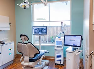 Dental exam room with blue and white dental chair, solea equipment, and window looking outside