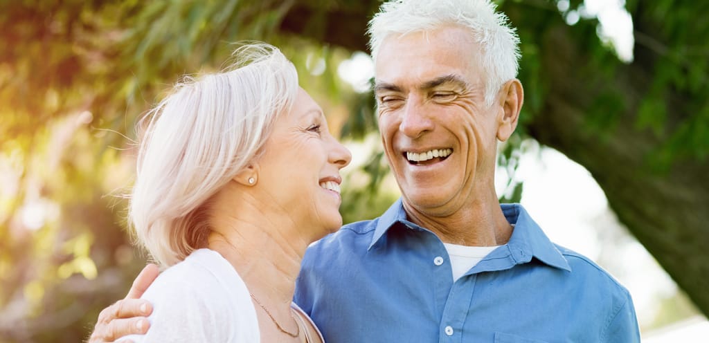 Older couple looking at each other while hugging and laughing outside