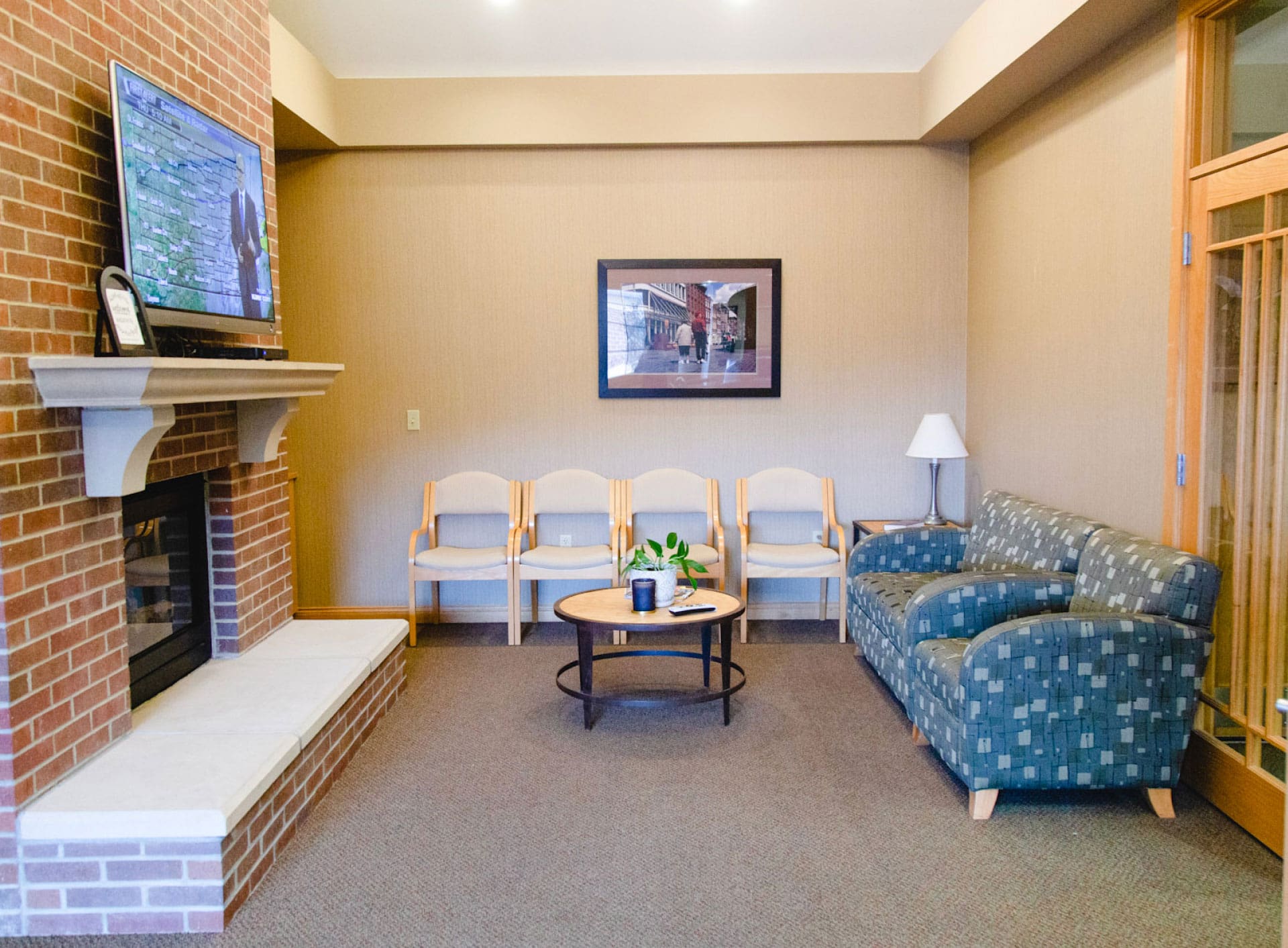 reception area with brick fireplace on left side, beige chairs along back wall and blue chairs on right wall