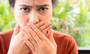 woman covering her mouth because her breath stinks