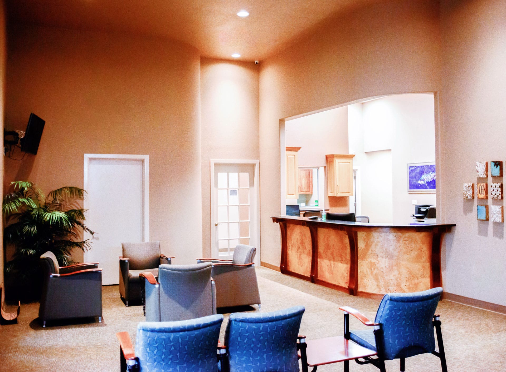 Office reception and front desk area with orange walls and blue chairs