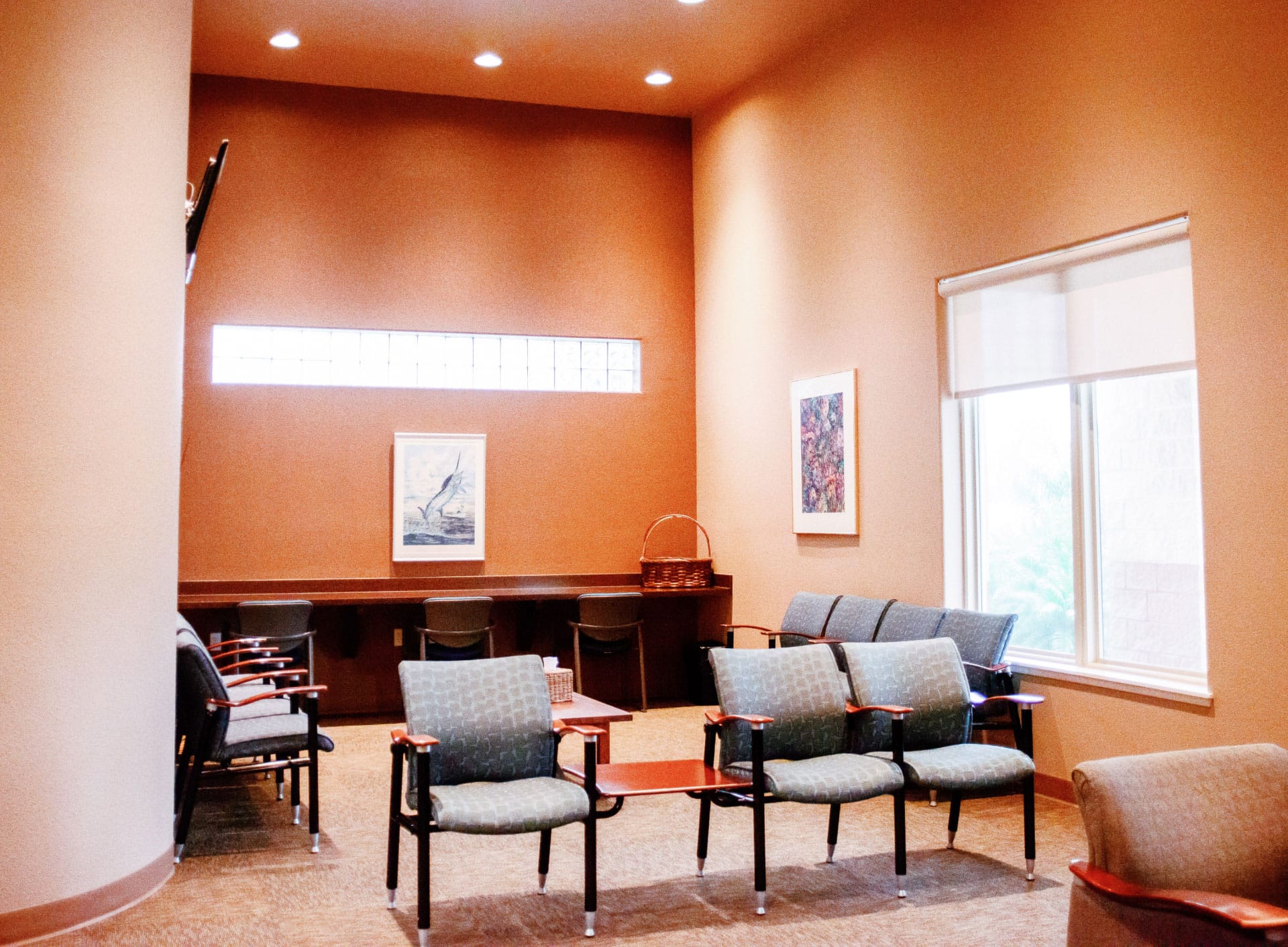 Office reception and front desk area with orange walls and gray chairs